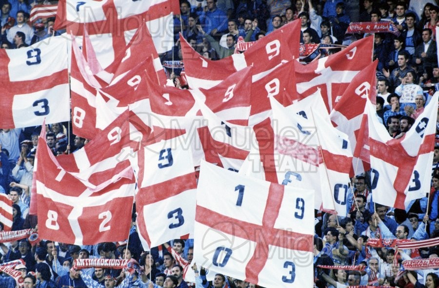 Aficionados de fútbol del Atletico de Madrid, en el estadio Vicente Calderón, agitando banderas conmemorativas del centenario del Club (Madrid) 2003.